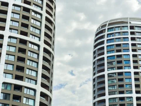 Two tall buildings with distinct architectural styles reach up toward a cloud 写真素材
