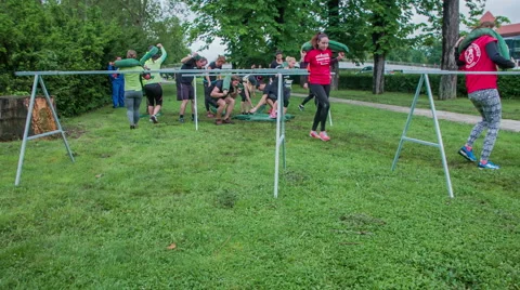 Two teams are going under hurdles with bags full of sand on their shoulders Vídeos de archivo 63360602