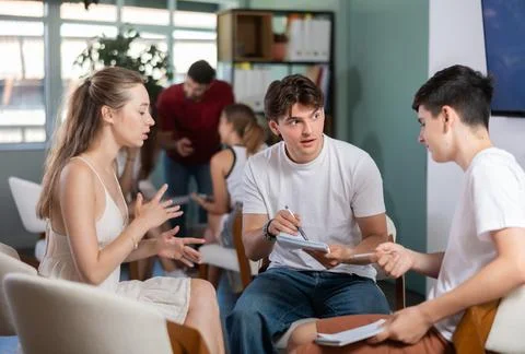 Two teams debating and discussing with teacher as game host in classroom Stock Photos