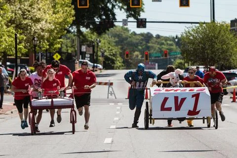 Two Teams Push Beds Down Street In Charity Fundraiser Event Foto stock