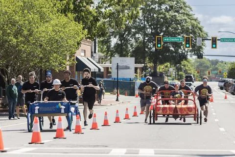 Two teams push beds down street in charity fundraising event Foto stock