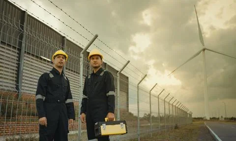 Two technician engineer in uniform with standing and checking wind turbine Foto stock