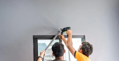 Two technicians are drilling a wall to install an air conditioner in a bedr.. Stock Photos