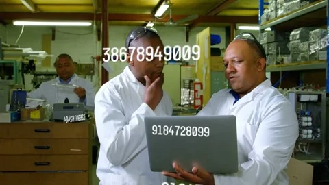 Two technicians holding laptop, checking production metrics in lab while numeric Stock Footage 334883912