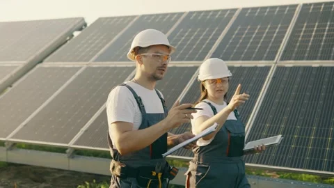 Two technicians lady and guy they walking through the solar panels rows. Stock Footage 257133794