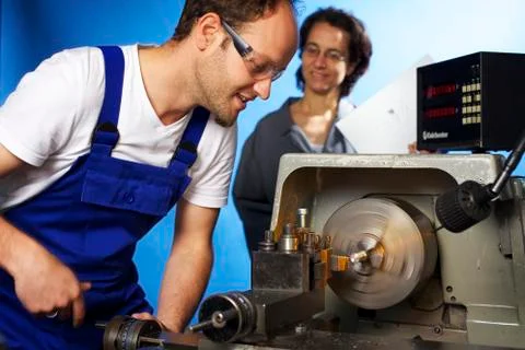Two technicians on lathe machine in workshop Stock Photos