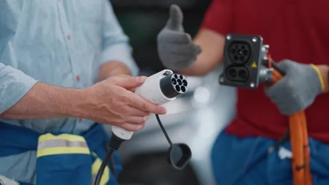 Two technicians show electric vehicle EV charging parts Stockbeeldmateriaal 339546351