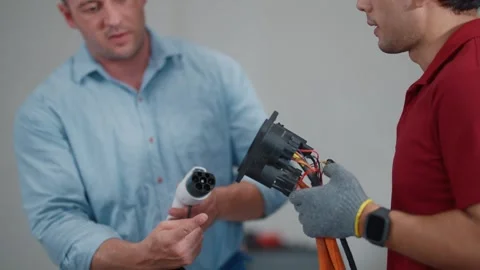 Two technicians show electric vehicle EV charging parts Vídeos de archivo 339546366