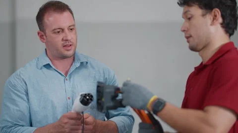 Two technicians show electric vehicle EV charging parts Vídeos de archivo 339546375