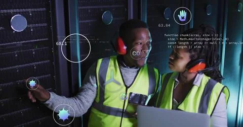 Two technicians wearing vests diagnosing racks in data center aisle, with laptop Stock Photos