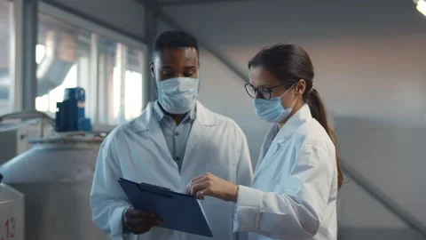 Two technologists in lab coats and mask at factory plant Stock Footage 143961014