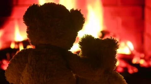 Two teddy bears are sitting hugging and looking at the fireplace flame. Stock-Footage 168387757