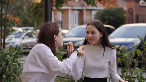 Two teenage friends biting the same hamburger at the same time, two friends Stock-Footage 231038319