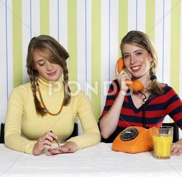 Two teenage girls (16-17), one using phone, the other painting nails, portrait Stock Photos