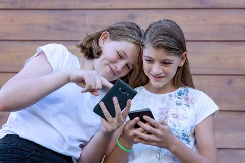 Two teenage girls have fun exchanging messages in social networks Stock Photos