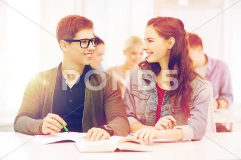 Two teenagers with notebooks and book at school Stock Photos