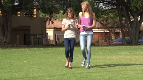 Two teenagers walking towards camera texting on smartphone Stock Footage 46375876
