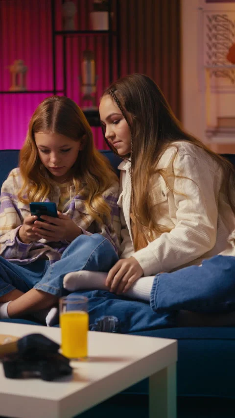 Two teens download and explore a new mobile app while resting on the sofa Stock Footage 300278060