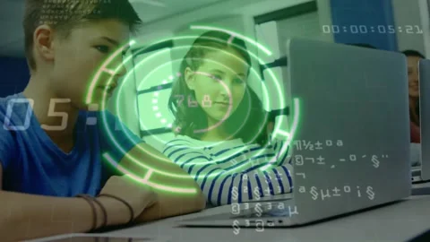 Two teens using trackpad and watching laptop, rotating green HUD tracking code Vídeo Stock 330717665
