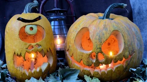 Two terrible pumpkins against dry leaves and an oil lamp Stock Footage 58995359
