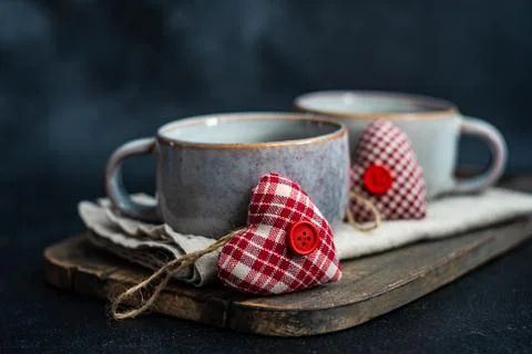 Two textile heart decorations next to ceramic mugs Stock Photos