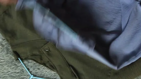 Two textured women's blouses attached to hangers were picked up one by one. Video stock 280494167