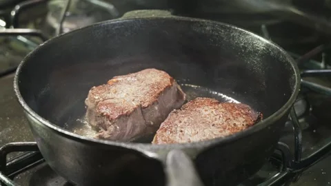 Two thick beef filet mignon steaks sear with a rich crust in a cast iron skillet Vídeos de archivo 348297179
