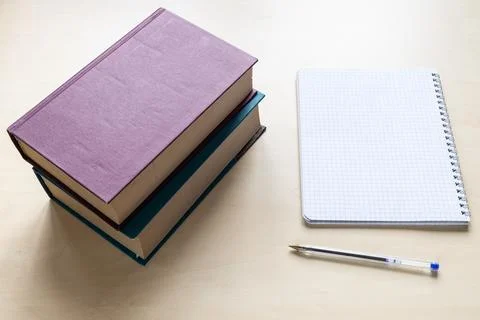 Two thick books, pen and blank spiral notebook Stock Photos