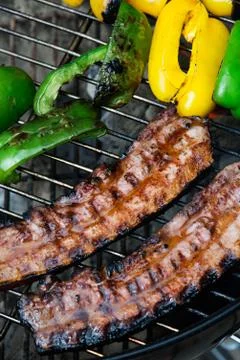 Two thick pieces of bacon with vegetables Stock Photos
