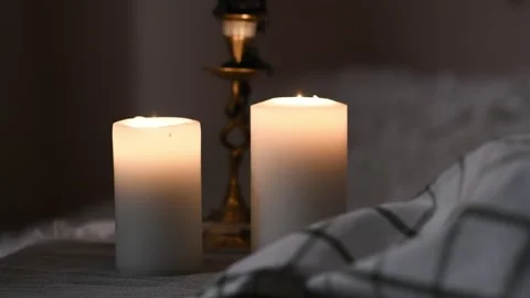 Two thick white candles slowly burning on a table in calm, dim atmosphere. Vidéo 309259548
