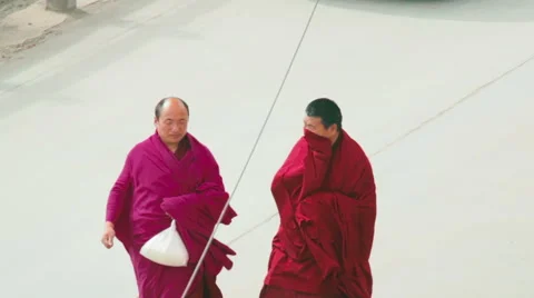 Two Tibetan Buddhist monks roam street of Labrang Monastery, China Stock Footage 57218203