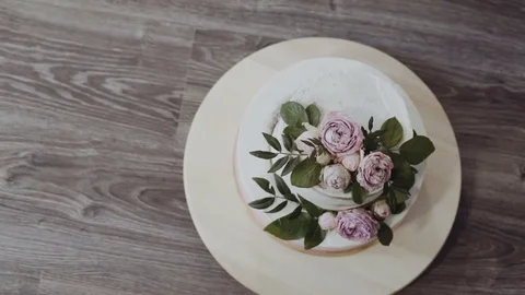 A two-tiered wedding cake, decorated with twigs of greenery and fresh flowers Stock Footage 75566190