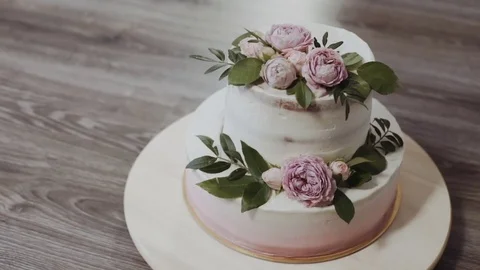A two-tiered wedding cake, decorated with twigs of greenery and fresh flowers Stock Footage 75566295