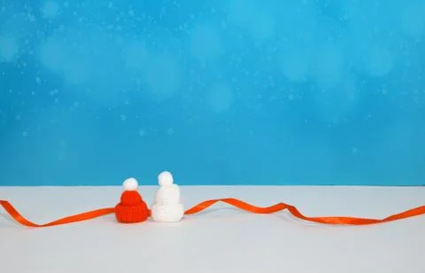 Two tiny white and red caps and red ribbon on blue background Stock Photos