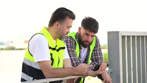 Two Tired Engineer Take A Break after work talking and watching mobile phon.. Stock Footage 262161382