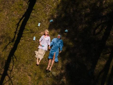 Two tired medics take off face masks while lying in forest Stock Photos
