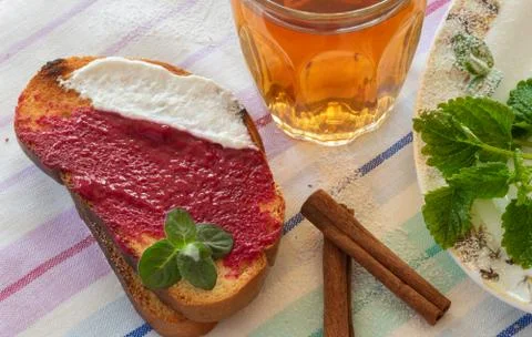 Two toast spread with raspberry mash and yogurt, glass of tea Stock Photos