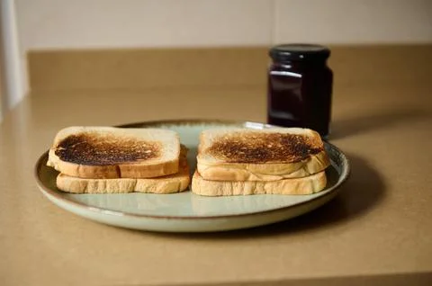 Two Toasted Bread Slices on a Plate with Jam Jar in Kitchen Stock Photos