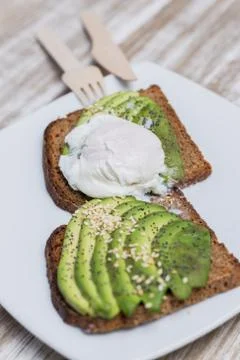 Two toasts with avocado and egg on a wooden table Stock Photos