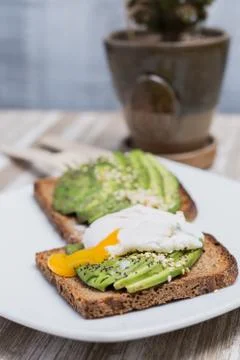 Two toasts with avocado and egg on a wooden table Stock Photos