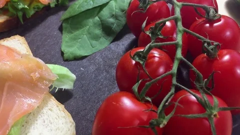 Two toasts with fresh salad and fish on the board. Near tomatoes Stock Footage 122496881