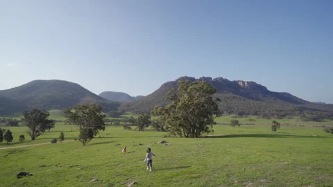 Two toddler kids playing on a vast field with hills as background 스톡 동영상 135108564