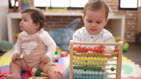 Two toddlers playing with abacus sitting on floor at kindergarten Stock Footage 222478621