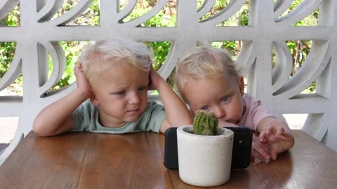 Two toddlers sitting at the table and watching entertaining cartoons Modern Stock Footage 166455122
