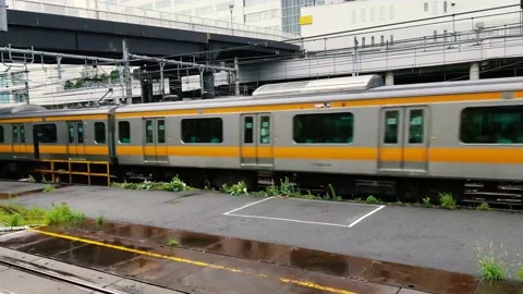 Two Tokyo trains passing by. The green and yellow trains Stock Footage 132460169