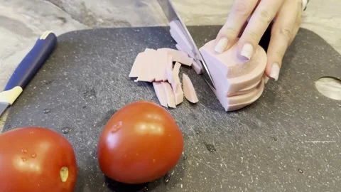 Two tomatoes are on a cutting board with a knife Vídeo Stock 283488391