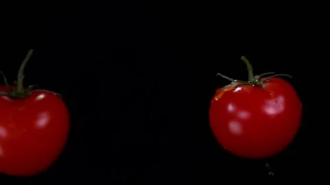 Two tomatoes are flying towards each other, colliding on the black background Stock Footage 131017318
