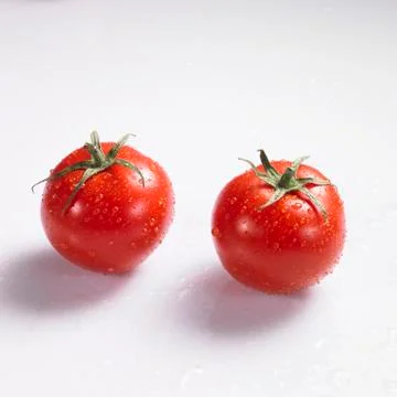 Two tomatoes with drops of water Stock Photos