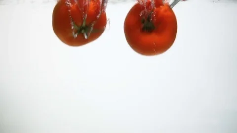 Two tomatoes sinking in water Stock Footage 84019486