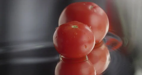 Two tomatoes slide and stop in the center Stock Footage 198561377